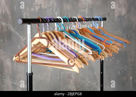 Kleiderstange mit Holz und bunten Kunststoff Kleiderbügel auf grauem Hintergrund Stockfoto