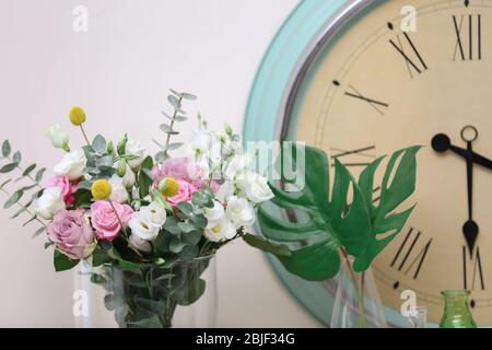 Schöne Komposition mit frischen Blumen und Vintage-Uhr auf hellem Hintergrund Stockfoto