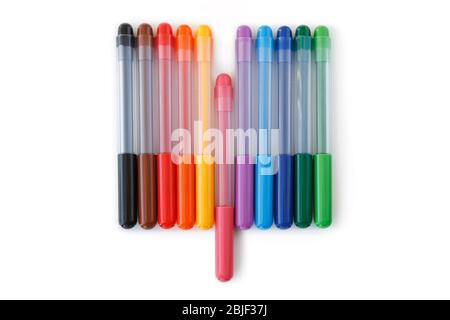 Nahaufnahme eines Sets von regenbogenfarbenen Markierstiften in einer Reihe, Draufsicht. Rosa Marker in der Mitte ist auseinander. Konzept des Aufstehens. Isoliert auf weiß. Stockfoto