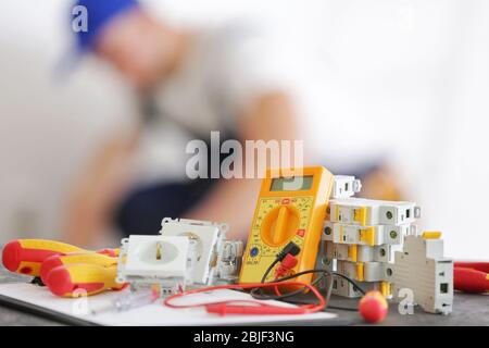 Set von Elektroinstallatern und verschwommenen Mann bei der Arbeit auf Hintergrund Stockfoto