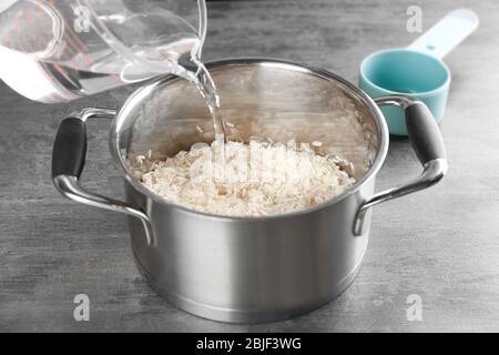 Kochkonzept. Wasser in den Topf mit Reis gießen Stockfoto