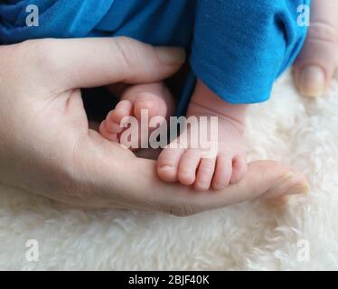 Kleine Kinder Füße in den Händen ihrer Eltern. Pflege der Gesundheit der Neugeborenen Stockfoto