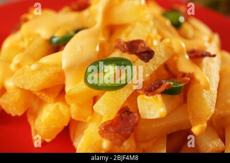 Leckere Käsefrites mit aufgeschnittenem Pfeffer und gebratenem Speck auf dem Teller, Nahaufnahme Stockfoto