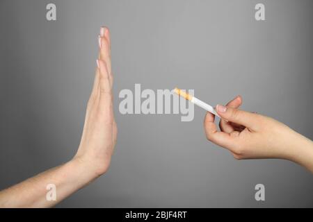 Rauchverbot. Frau weigert sich, eine Zigarette auf grauem Hintergrund angeboten zu haben Stockfoto