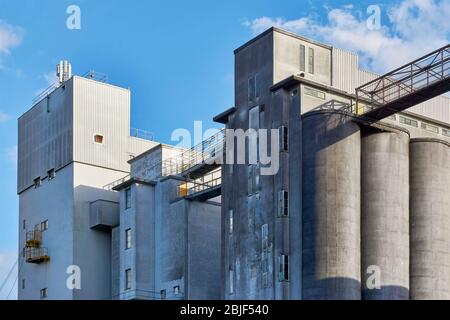 Alte Industriegebäude aus Beton vor blauem Himmel. Konzept der Rezession oder Wirtschaftswachstum. Stockfoto