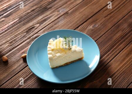 Stück köstlicher Käsekuchen mit Zitrone auf Holztisch Stockfoto