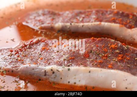 Nahaufnahme von marinierten Steaks mit Gewürzen Stockfoto