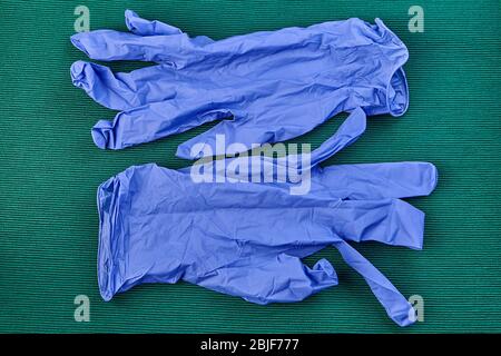 Schutzhandschuhe aus Latex in blau für Sanitäter, grüner Hintergrund. PSA für Gesundheitsdienstleister während der COVID-19-Pandemie. Stockfoto