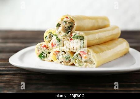 Köstliche gefüllte Cannelloni in Teller auf Holztisch Stockfoto