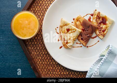 Selektiver Fokus. Leckeres Frühstück mit Pfannkuchen und Orangensaft auf Holztablett Stockfoto