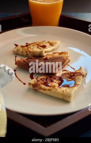 Selektiver Fokus. Leckeres Frühstück mit Pfannkuchen und Orangensaft auf Holztablett Stockfoto