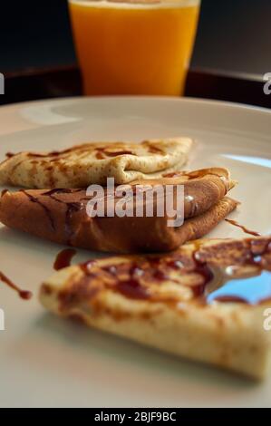 Selektiver Fokus. Leckeres Frühstück mit Pfannkuchen und Orangensaft auf Holztablett Stockfoto