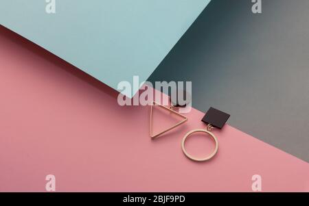 Geometrisches Design goldene Ohrringe auf rosa und blauem Papier Hintergrund Stockfoto