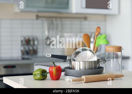 Küchenutensilien, Kochgeschirr und Paprika auf Holztisch Stockfoto