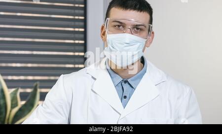 Junger männlicher Arzt Wissenschaftler mit Maske Porträt im Krankenhaus Stockfoto