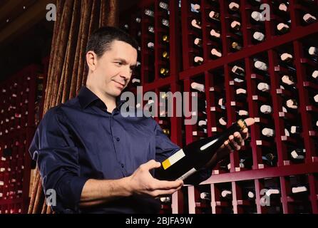 Männlicher Sommelier, der Wein im Keller auswählt Stockfoto