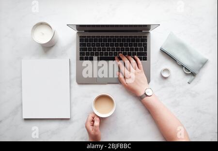 Top Down Ansicht Frau auf einem Laptop mit einem Kaffee-Tasse tippen. Stockfoto