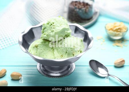 Leckeres Pistazien-Eis in Schale und Nüsse auf Holztisch Stockfoto