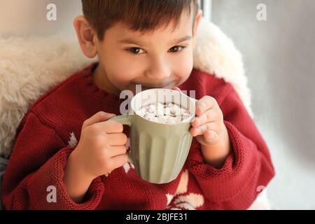 Niedlichen kleinen Jungen trinken heiße Schokolade mit Marshmallow zu Hause Stockfoto