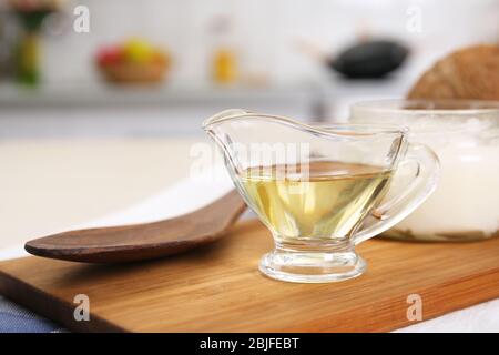 Sauceboat mit geschmolzenem Kokosöl auf Holzbrett Stockfoto