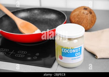 Kokosöl im Glasgefäß und Bratpfanne auf Hintergrund Stockfoto