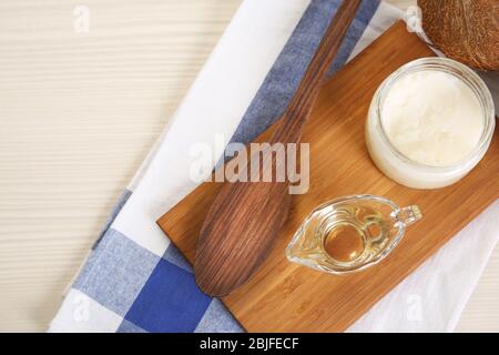 Sauceboat mit geschmolzenem Kokosöl auf Holzbrett Stockfoto