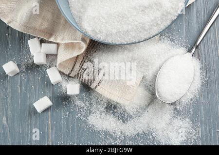 Schüssel und Löffel mit Zucker auf Holzhintergrund Stockfoto