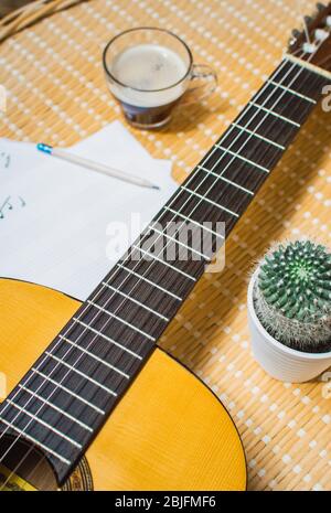 Schöne Draufsicht auf eine klassische Gitarre, Musik-Notizbuch, Kaffee und Kaktus. Entspannender Tag des Komponierens von Musik zu Hause. Stockfoto