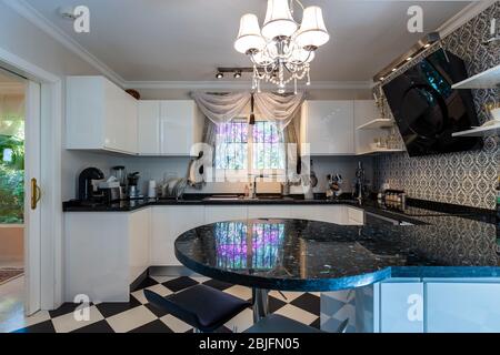 Stilvolle Küche in Schwarz- und Weißtönen. Schwarz-weißer Marmor, Küchenausstattung, weiches Licht. Stockfoto