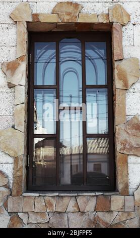 Großes Fenster mit Metallgitter auf Steinwand Hintergrund Stockfoto