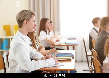 Schüler, die im Klassenzimmer am Schreibtisch sitzen Stockfoto