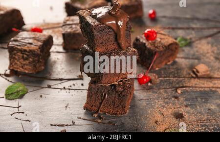 Geschmolzene Schokolade auf schmackhafte Brownies auf dem Tisch gießen Stockfoto