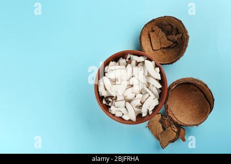 Schale mit Kokosnussspäne und Schale auf farbigem Hintergrund Stockfoto