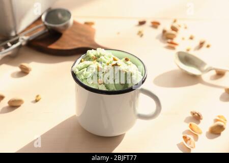 Pistazien Eis mit gehackten Nüssen in Becher auf Holztisch Stockfoto