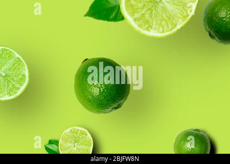 Set aus frischen reifen ganzen und schneiden Limes mit Blättern und Scheiben auf hellem grünen Hintergrund. Draufsicht. Kreative Obstkomposition Stockfoto