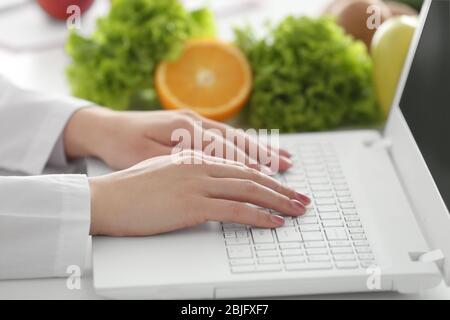 Junge Ernährungswissenschaftlerin arbeitet auf Laptop im Büro, Nahaufnahme Stockfoto
