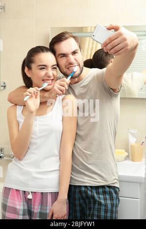 Junge glückliche Paar unter Selfie beim Zähneputzen im Badezimmer Stockfoto