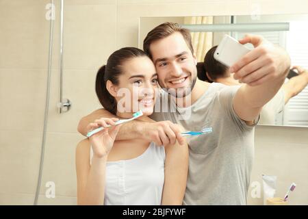 Junge glückliche Paar unter Selfie beim Zähneputzen im Badezimmer Stockfoto