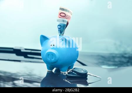 Keramik Sparschwein mit Banknote auf Haube des Autos Stockfoto