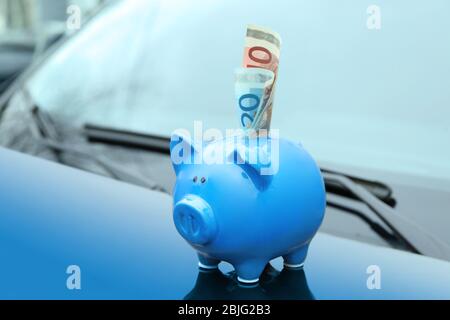 Keramik Sparschwein mit Banknote auf Haube des Autos Stockfoto