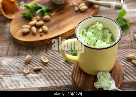 Becher mit leckerem Pistazien-Eis auf Holztisch Stockfoto