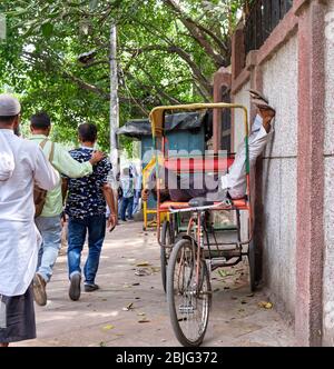 Neu Delhi / Indien - 19. September 2019: Fahrer schläft auf seiner Fahrrad-Rikscha in den Straßen von Neu Delhi, Indien Stockfoto