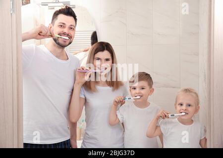 Das junge Paar und ihre Kinder putzen im Badezimmer die Zähne Stockfoto