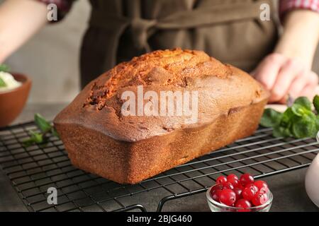 Kühlgitter mit frisch gebackenem Joghurtkuchen und Frau auf dem Hintergrund Stockfoto