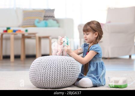 Nettes kleines Mädchen spielen mit Vernebler zu Hause. Allergiekonzept Stockfoto