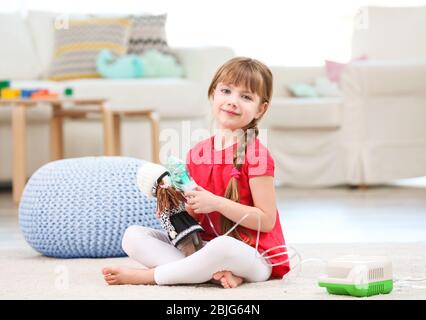 Nettes kleines Mädchen spielen mit Vernebler zu Hause. Allergiekonzept Stockfoto