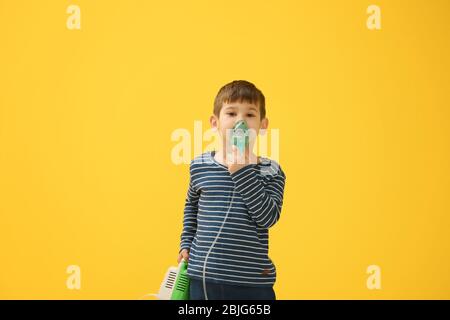 Niedlichen kleinen Jungen mit Vernebler auf farbigen Hintergrund. Allergiekonzept Stockfoto