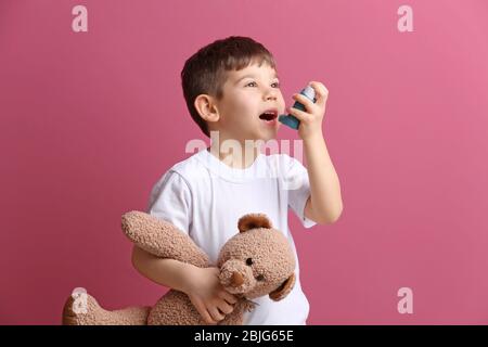 Niedlichen kleinen Jungen hält Inhalator und Spielzeug Bär auf farbigen Hintergrund. Allergiekonzept Stockfoto