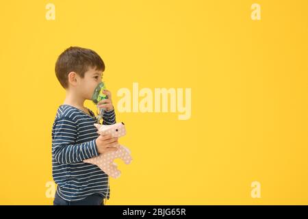 Niedlichen kleinen Jungen mit Vernebler auf farbigen Hintergrund. Allergiekonzept Stockfoto