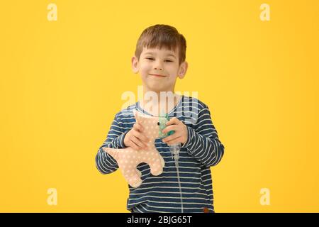 Niedlichen kleinen Jungen hält Vernebler und Spielzeug auf farbigen Hintergrund. Allergiekonzept Stockfoto